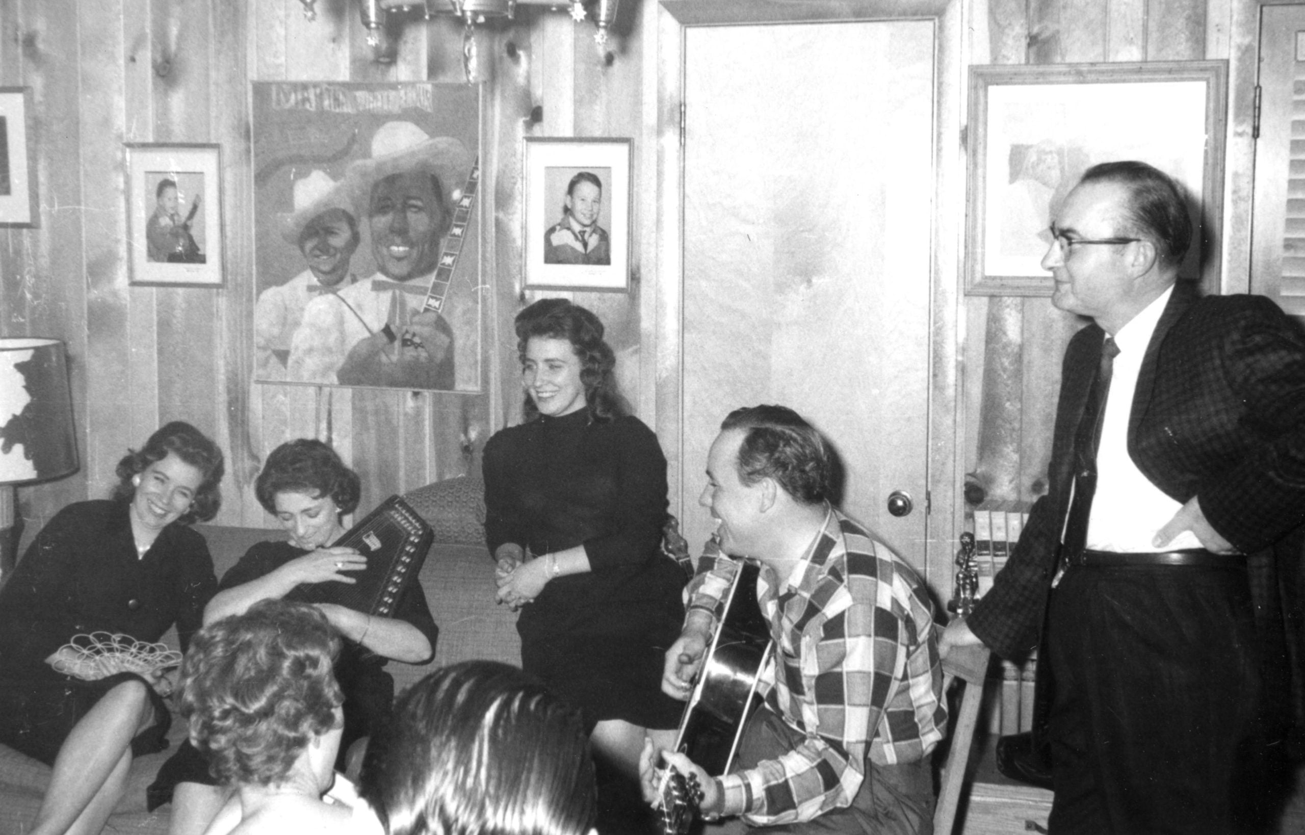 Earl Scruggs plays the guitar with Mother Maybelle Carter on the auto harp and her daughters Anita and June beside her on the couch. Photo Courtesy of the Earl Scruggs Center