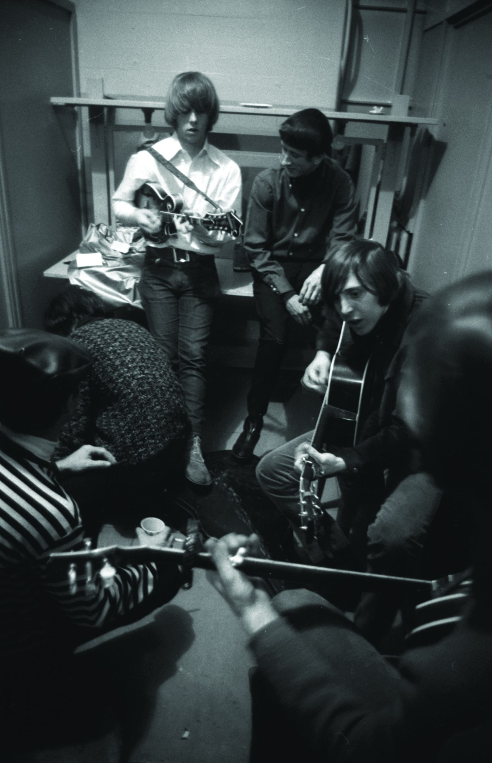 Bottom – Chris Hillman backstage with the Dillards in 1966.  Doug Dillard is playing banjo, Rodney Dillard on guitar, and Chris Hillman plays Dean Webb’s mandolin as Dean watches over his shoulder. Photo courtesy of Sony Music Archives.*