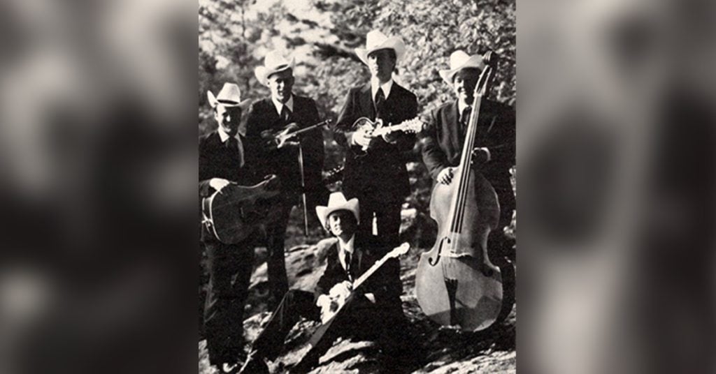 Group photo of the band sitting outside with their instruments
