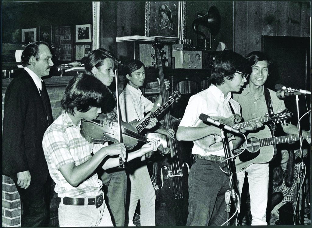 Bluegrass 45 performing at a jam party at Tex Logan’s home in New Jersey in 1971.  Tex Logan stands behind the band.  Mandolin player Akira Otsuka is playing Bill Monroe’s mandolin.  //  Photo by Ron Petronko