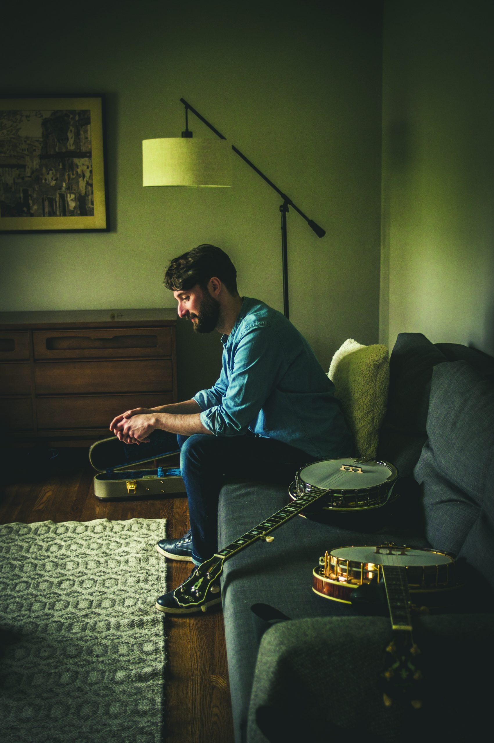 Corbett sits on his living room couch with his banjo lying next to him.
