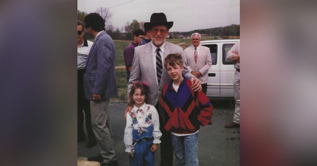 Laura (five years old) with Doyle Lawson and her brother Nathan (notice Paul Williams photo-bombing in the background in front of the white van).