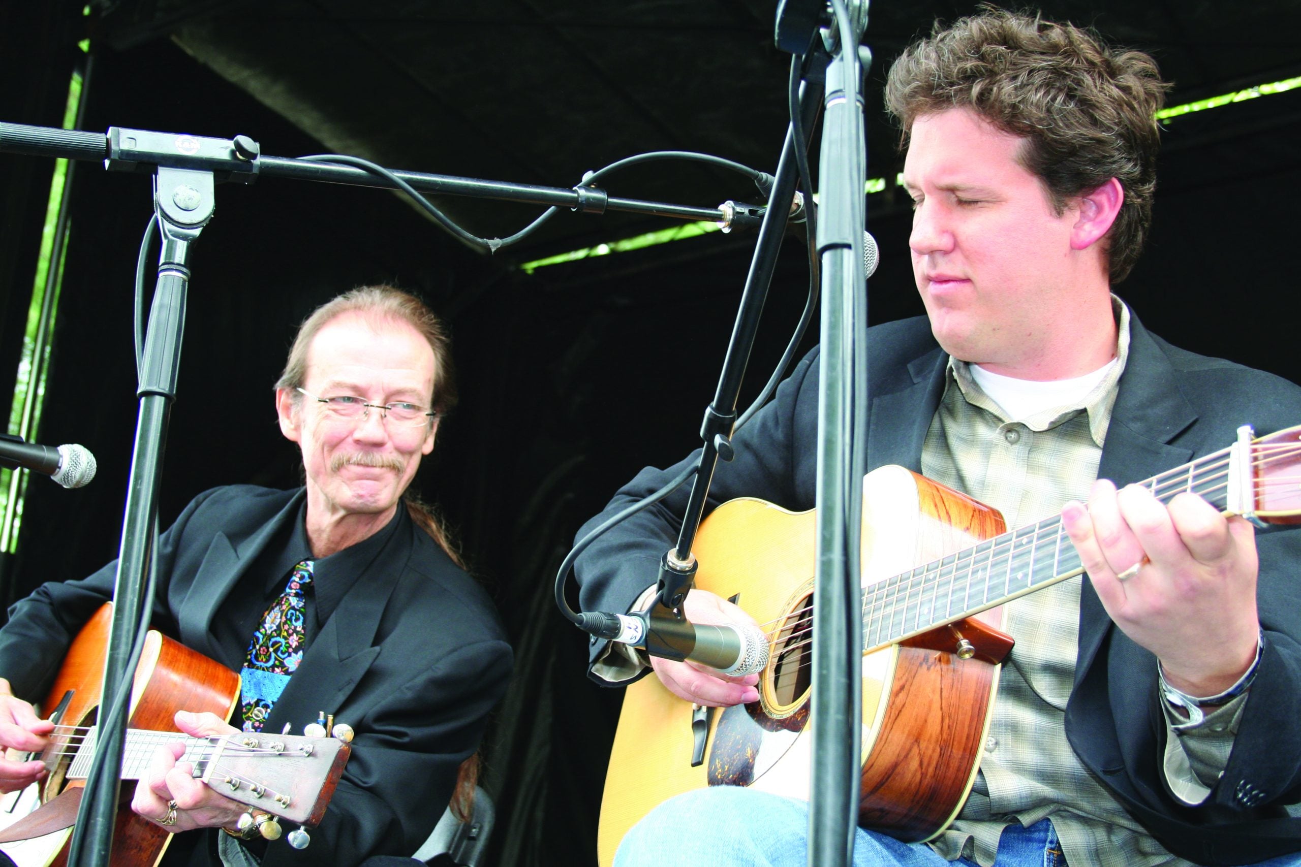 Tony Rice and Bryan Sutton playing their guitars on stage