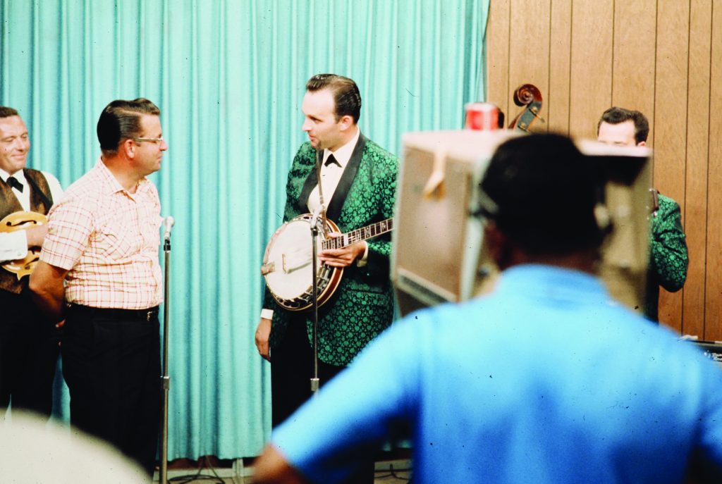 Bill Emerson (banjo) conversing Delmar Delaney on the set of Wally Horton’s Hayloft, ca. July 1968. At left is Garland Alderman, Cliff Waldron appears (partially hidden) at far right. (Photo courtesy of the Emerson Family.