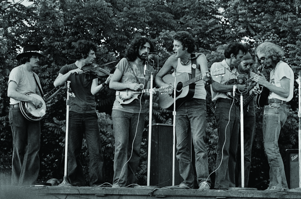 The Culpeper-Warrenton Bluegrass Festival in Warrenton, Virginia in 1973.  Butch Robins, John Hartford, David Grisman, Peter Rowan, Buck White, Ebo Walker and Sam Bush. Regarding this on-stage jam, Rowan said, “The only one missing is Jerry.” Photo by Phil Zimmerman Courtesy of Bluegrass Music Hall of Fame & Museum.
