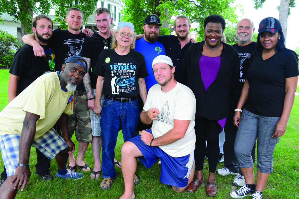 Veterans’ Initiative Group Photo from 2015:  The stained-glass artist “Ragtime” (a Vietnam War Vet) is standing 4th from the left with the blue bandana and the Veterans Initiative leader, Josh Hisle (an Iraq War Vet) is in the royal blue T-shirt and ballcap standing beside him, 5th from left. 
Photo by Pamela Zappardino
