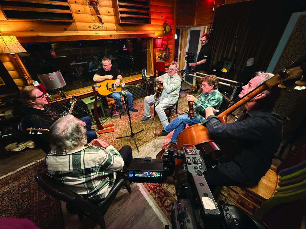 Brandon Lee Adams in the studio working on his new album.  Joining Brandon clockwise around the circle are Vince Gill, Tim O’Brien, Glenn Worf, John McEuen and John Jorgenson.  Photo by Mindy Adams