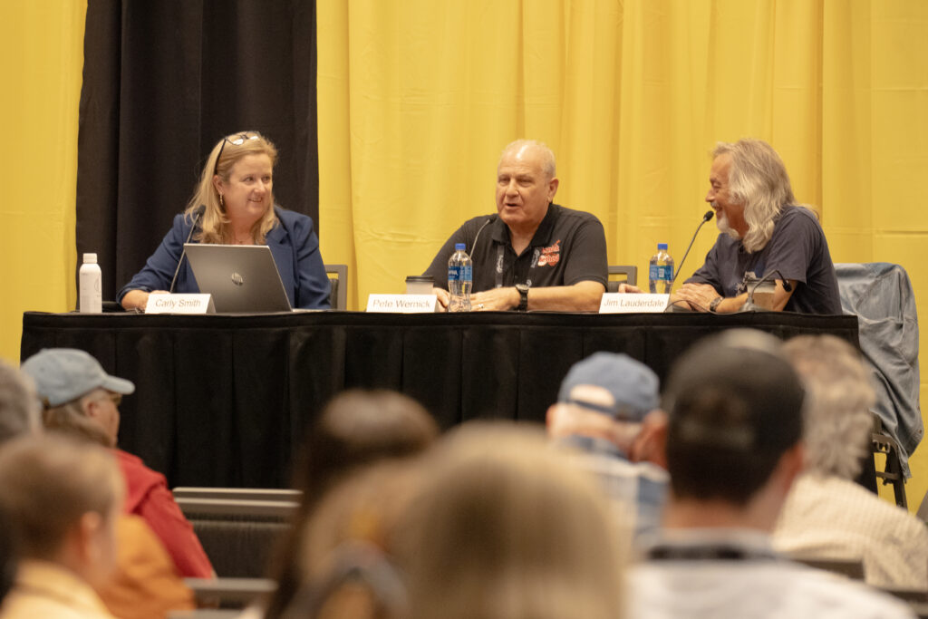 Pete Wernick (middle), who became the President of IBMA in 1986 and held that position until 2001, speaks at a IBMA panel discussion in 2024 with Carly Smith (to his right) and Jim Lauderdale (to his left).