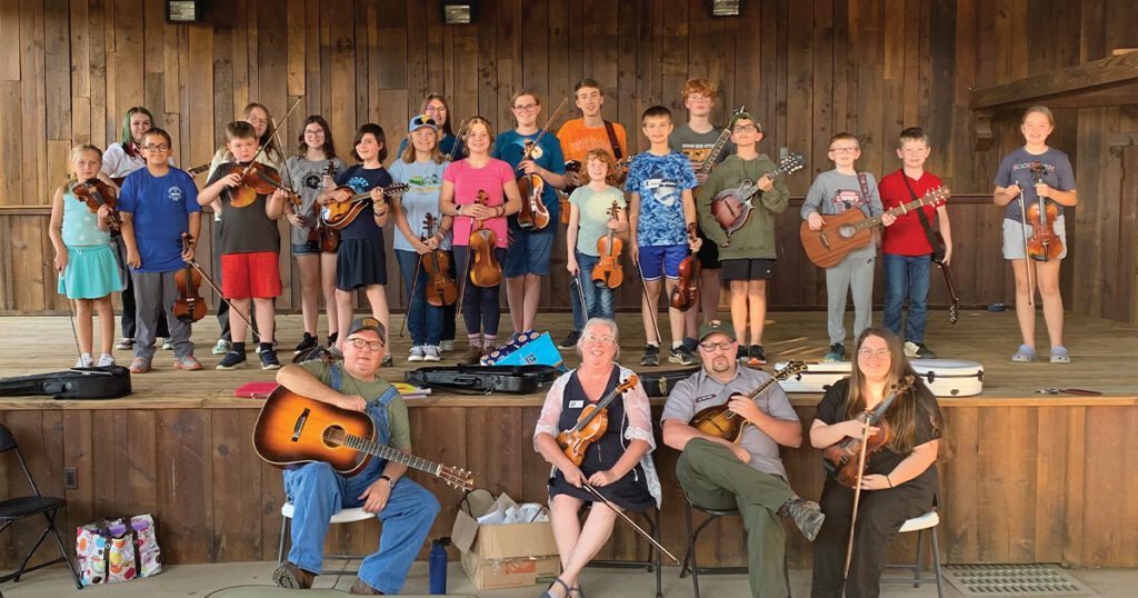 Smoky Mountain J.A.M. students perform at the Great Smoky Mountains Heritage Center in Townsend, Tennessee last fall, led by affiliate director Sarah Pirkle (center, with fiddle). Photo courtesy of Junior Appalachian Musicians