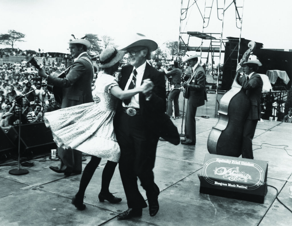 Bill Monroe dancing on stage at the Kentucky Fried Chicken Bluegrass Music Festival in Louisville, Kentucky.  Bluegrass Music Hall of Fame & Museum collection.